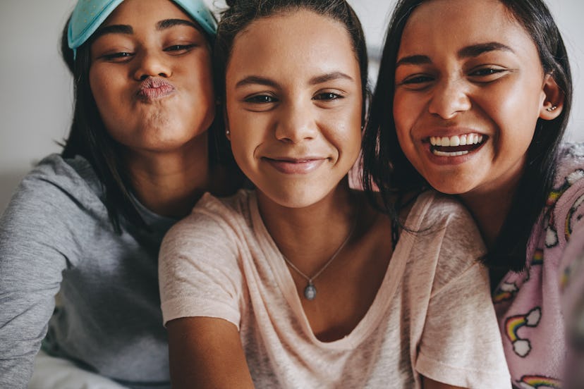 Three young girls sitting together posing for a selfie during a sleepover. Girls having a good time ...