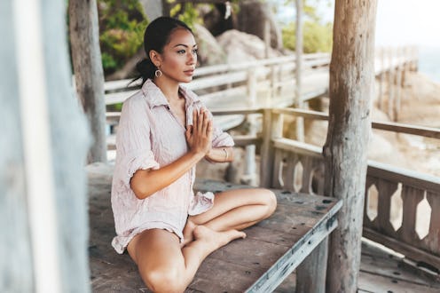 Young woman meditating in a yoga pose in a gazebo at the beach