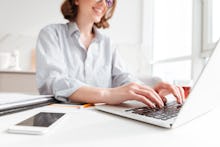 Cropped photo of pretty brunette woman typing email on laptop computer while sitting at home, select...