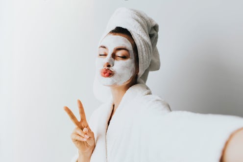 woman has fun with a facial mask.Self portrait of charming, stylish, pretty, model after bath wrappe...