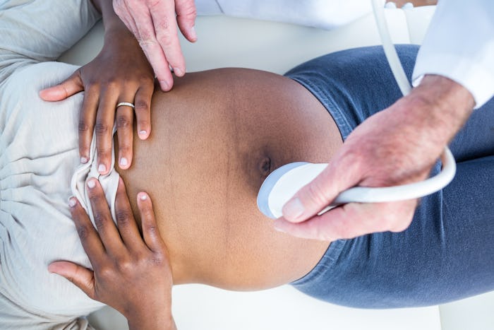 Overhead view of doctor doctor performing ultrasound on pregnant woman in clinic