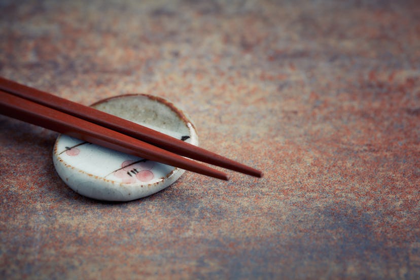 Wooden chopsticks and chopstick rest on rustic background. Close up. Copy space. 