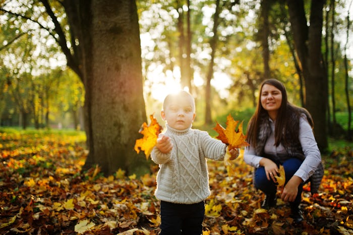 Mom with son on majestic autumn fall forest.