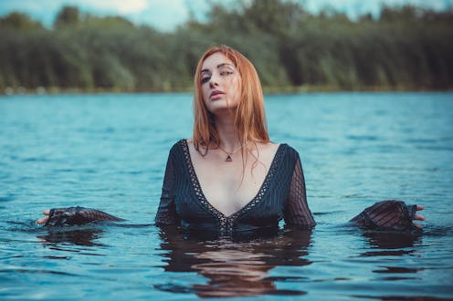 Sexy mystical woman in black bodysuit in water. Concept of femininity and sensual