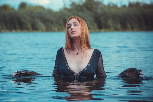 Sexy mystical woman in black bodysuit in water. Concept of femininity and sensual
