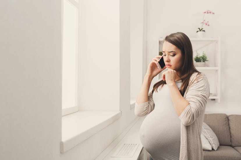 Worried pregnant woman talking on phone copy space. Sad expectant lady having serious conversation w...