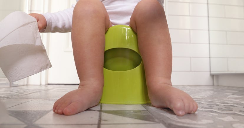 Funny baby boy sitting on chamberpot, Children's legs hanging down from a chamber-pot. Kid plays toi...