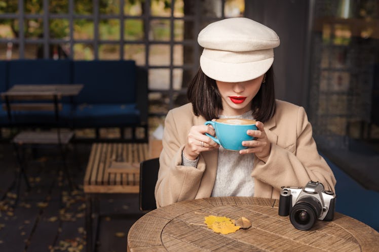 Mysterious woman in a hat is drinking coffee