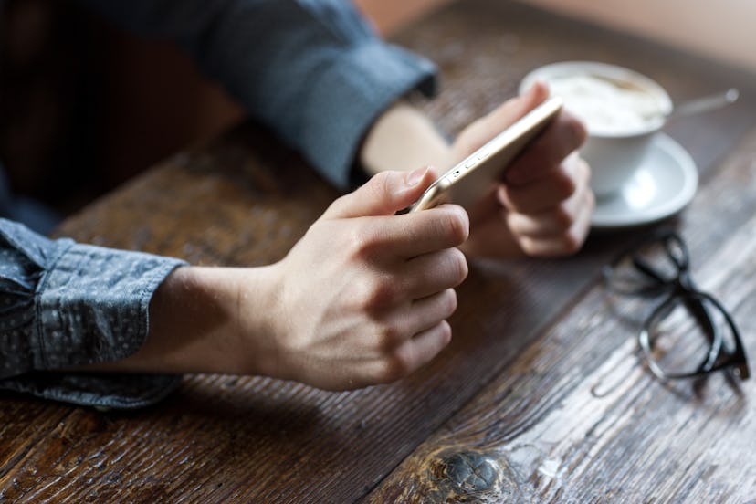 Young man at the bar having a coffee break and texting with his mobile