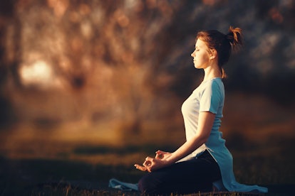 Woman meditating in the rays of the setting sun.