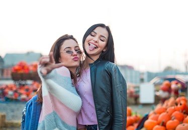 Pumpkin puns for Instagram are great for these two women posing in a pumpkin patch, one holding her ...