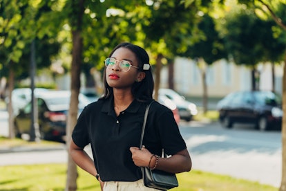 Young cool black skin girl with glasses walking in the street in the sammer day.