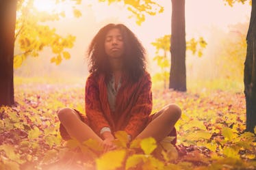 Young black woman relaxing in the autumn forest on a sunny day.