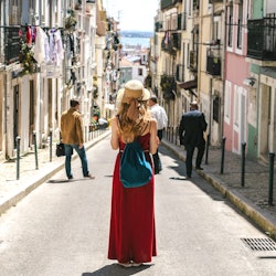 Young travel woman is walking on the beautiful old cozy street of Lisbon in Portugal