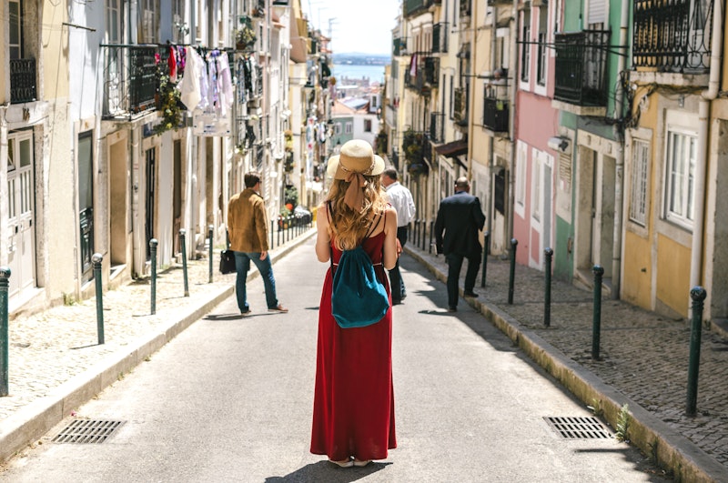 Young travel woman is walking on the beautiful old cozy street of Lisbon in Portugal