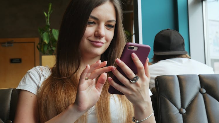 Close-up portrait of young beautiful woman use mobile phone in cafe, swipe and smile