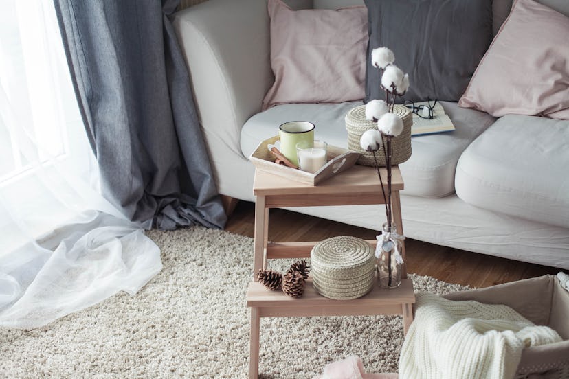 Home decor. A wooden bedside table, a sofa, a cotton, a mug of hot coffee, a knitted plaid. Warm hou...