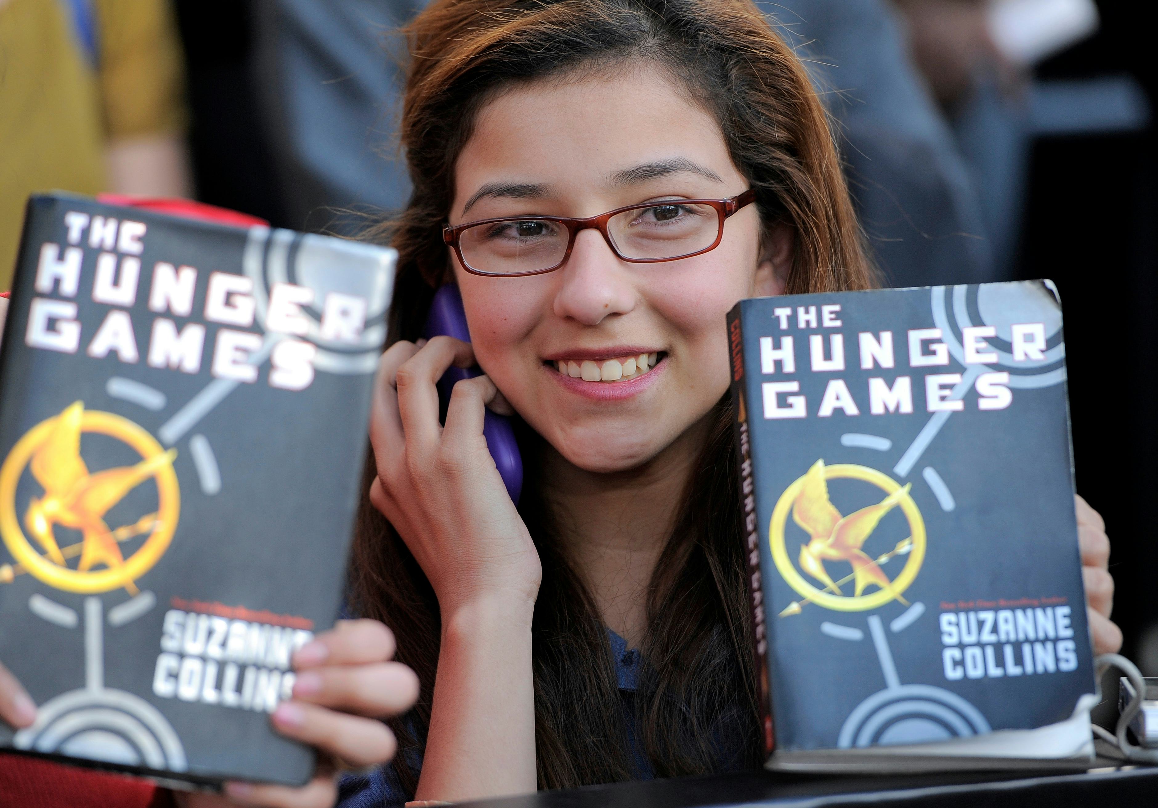A Hunger Game fan holds up a copy of the Hunger Games book at the world premiere of "The Hunger Game...