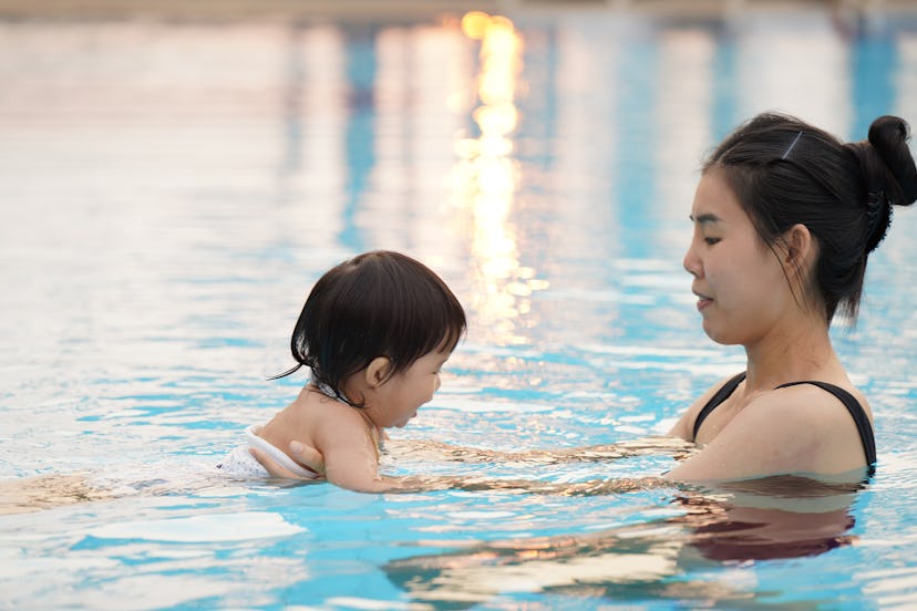 Mother is teaching her kid to swim.