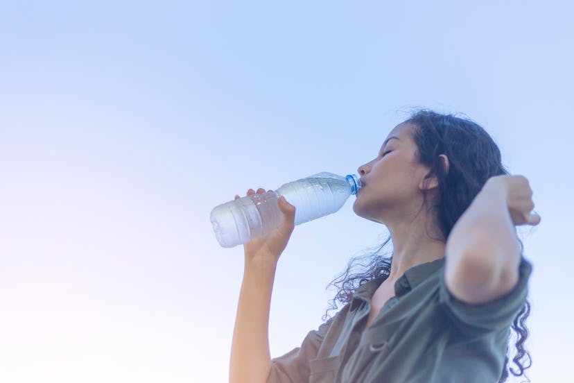 Happy beautiful young Asian woman drinking water with a plastic bottle in her hand. clean water are ...
