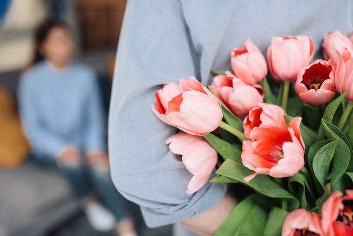 Unexpected moment in routine everyday life! Cropped photo of man's hands hiding holding chic bouquet...