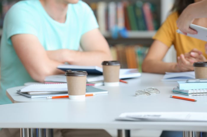 Young people studying at table in library, closeup
