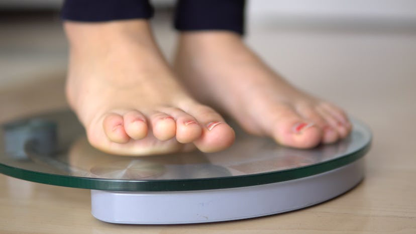 woman feet standing on weigh scales, weight loss diet