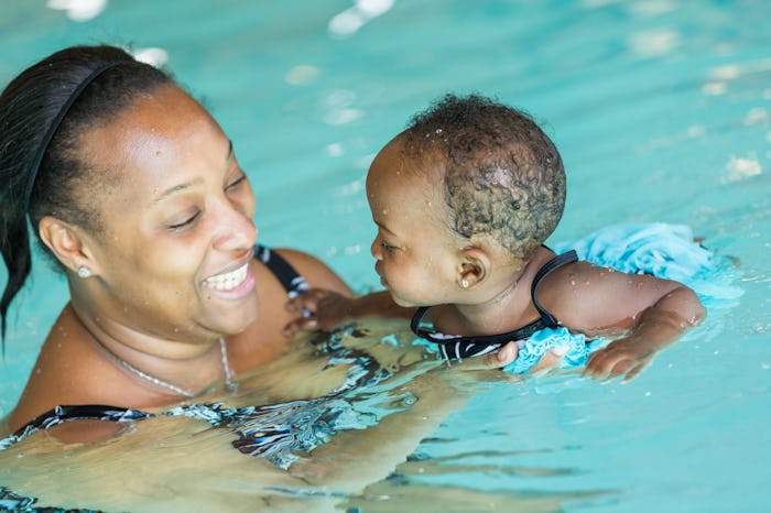 Cute baby girl learning how to swim in indoor pool.
