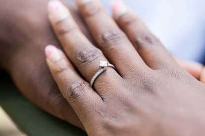 Hands of an nigerian couple. She is wearing an engagement ring. 