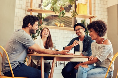 Young friends having a great time in restaurant. Group of young people sitting in a coffee shop and ...