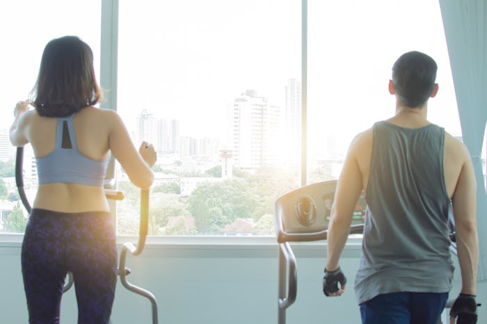 Back of a couple is exercising in fitness center in the morning with the warm light and cityview out...