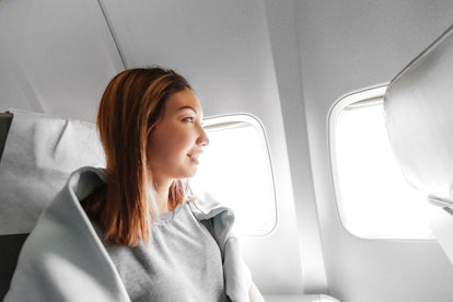 Young asian woman looking at the window in air plane, travel and transport concept