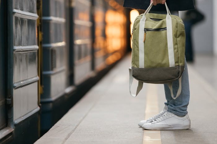 Close up photo of male waiting subway train on platform. Well-dressed handsome man in white sneakers...