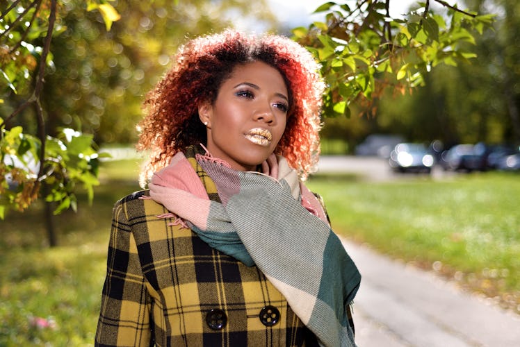 portrait of pretty dark-skinned beautiful girl with red curly magnificent hair. woman in plaid coat ...
