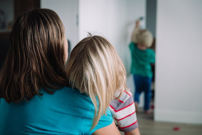 mom comforting crying daughter while sister feeling hurt
