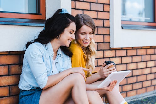 happy woman pointing with finger at digital tablet near girl