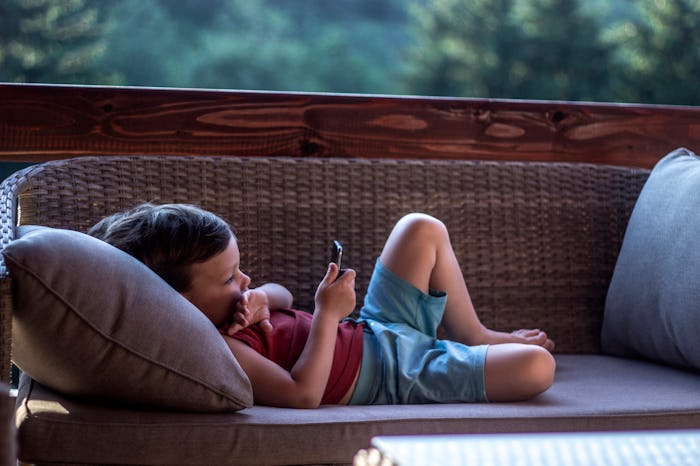 Small three years old toddler boy addictive on smartphone. Child is using mobile phone. Kid having f...