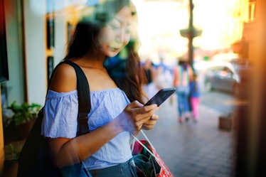 Young asian woman texting on her phone in the city. 