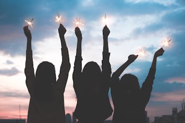 silhouette happy group of asian young girl friends hangout enjoy and play sparklers firework at nigh...