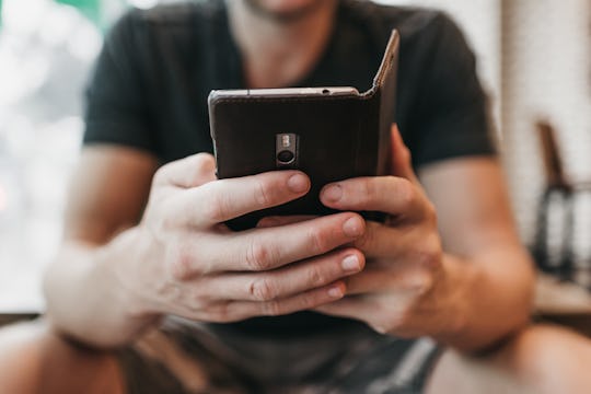 A man looking at a smartphone that he is holding in his hands