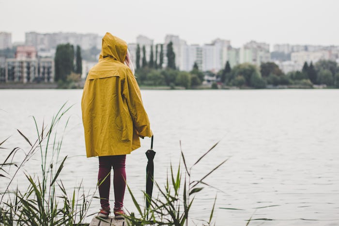 autumn gray rainy day concept of young teenager person in yellow raincoat stay back to camera on sma...
