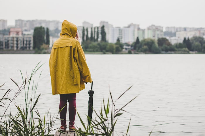 autumn gray rainy day concept of young teenager person in yellow raincoat stay back to camera on sma...