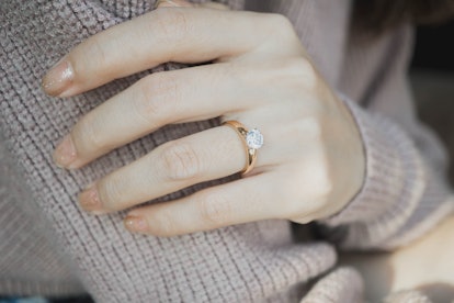Close up of an elegant engagement diamond ring on woman finger with dark pink sweater winter clothe....