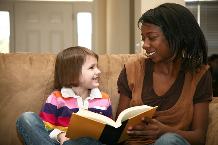 Beautiful african american woman reading to a 5 year old girl at home.