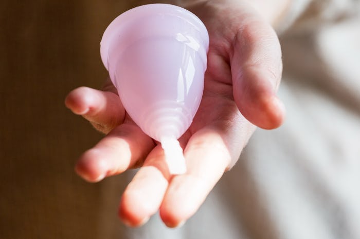 Pink menstrual cup hold in woman's hands.