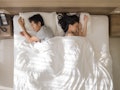 Top view of sad Asian couple sleeping together, thinking about relationship problems, and suffering ...