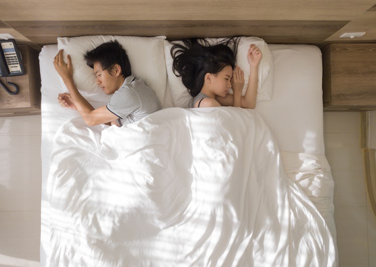 Top view of sad Asian couple sleeping together, thinking about relationship problems, and suffering ...