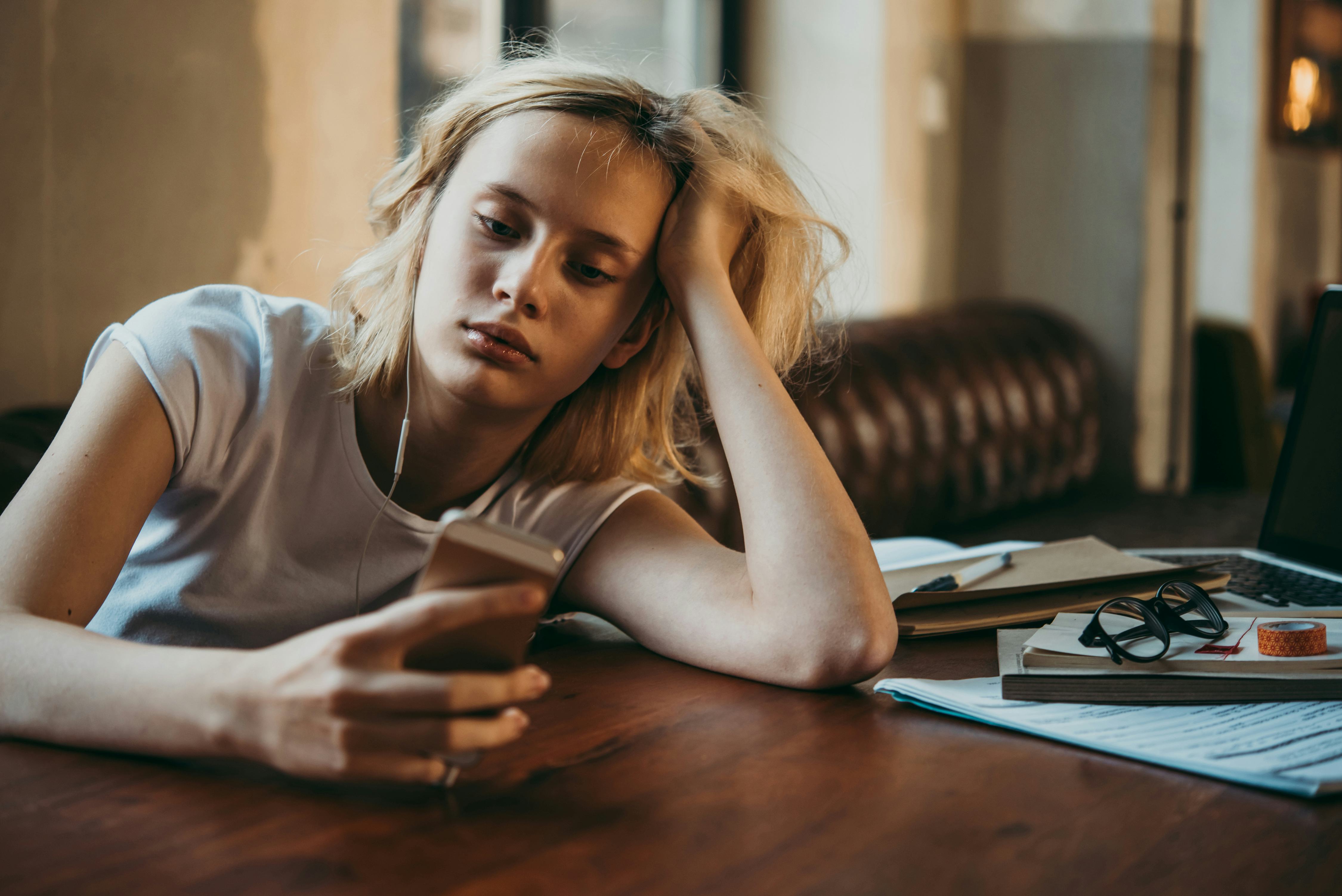 A teenage girl listening to music and looking at her smartphone. Procrastination and laziness concep...