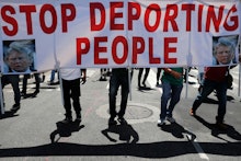 Protesters cast shadows as they walk with a sign during a May Day rally, in Los Angeles. Thousands o...