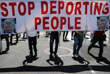 Protesters cast shadows as they walk with a sign during a May Day rally, in Los Angeles. Thousands o...